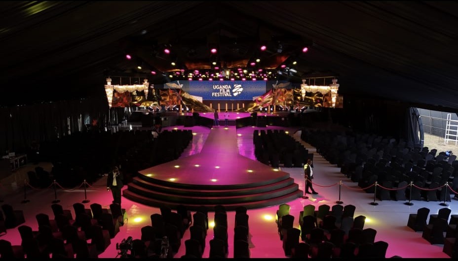 Festival marquee interior with pink lighting, stage and audience seating